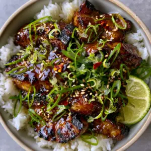 Overhead close-up of Ginger Lime Pork medallions with charred edges and a glistening honey glaze on a bed of jasmine rice.
