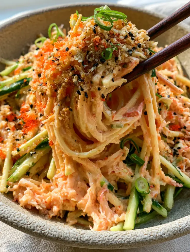 Cucumber Crab Salad: The Ultimate Spicy Kani Salad with Signature Crunch 2 Close-up of wooden chopsticks lifting shredded imitation crab and julienned cucumber from a Cucumber Crab Salad.