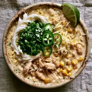 Close-up of White Chicken Chili showing the thick ivory broth, shredded chicken, and golden corn kernels.