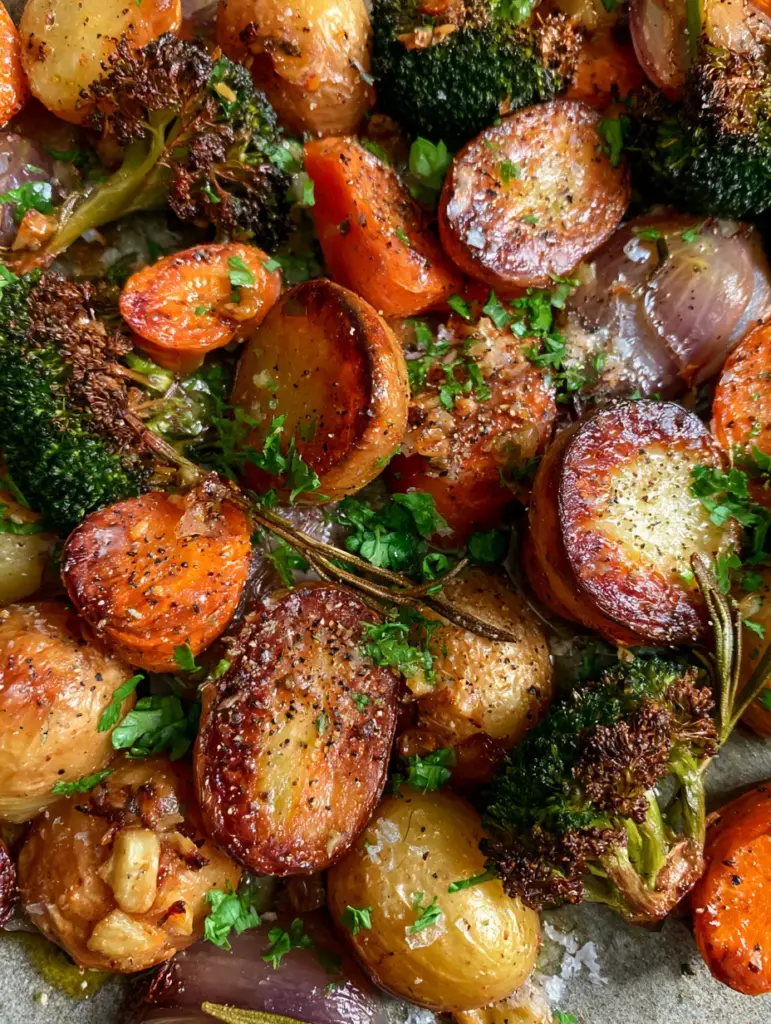 Rustic sheet pan filled with Garlic Herb Roasted Potatoes and Veggies including charred broccoli and toasted garlic.