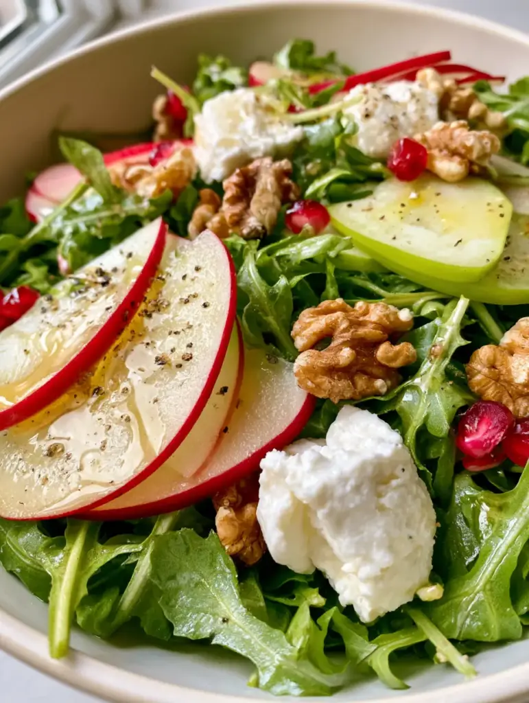 Extreme macro close-up of vibrant Apple Arugula Salad showing translucent apple slices and glistening baby arugula leaves.